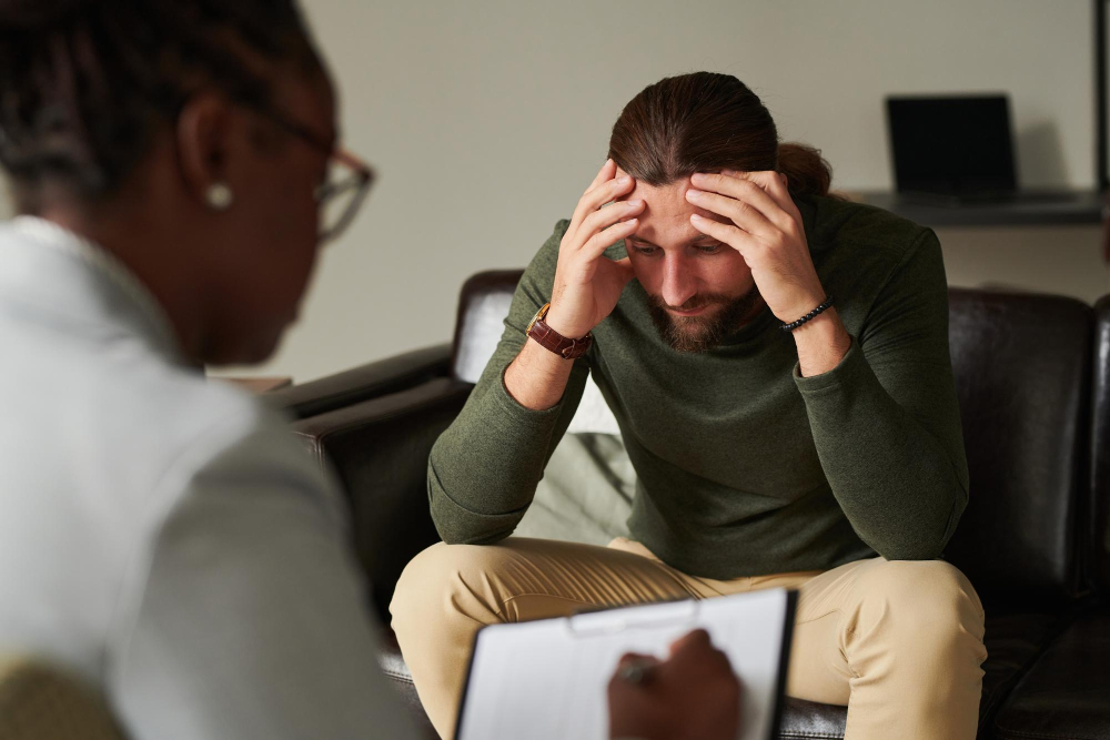 Man discussing emotional challenges with a therapist while exploring when to go to inpatient mental health treatment.