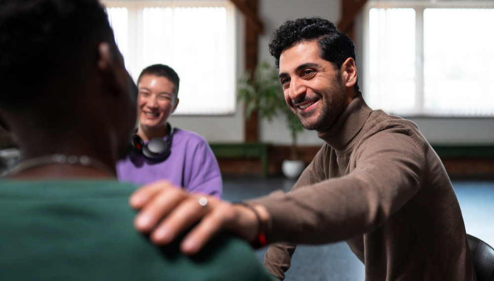 Man supporting another participant during a group therapy session for IOP addiction treatment.
